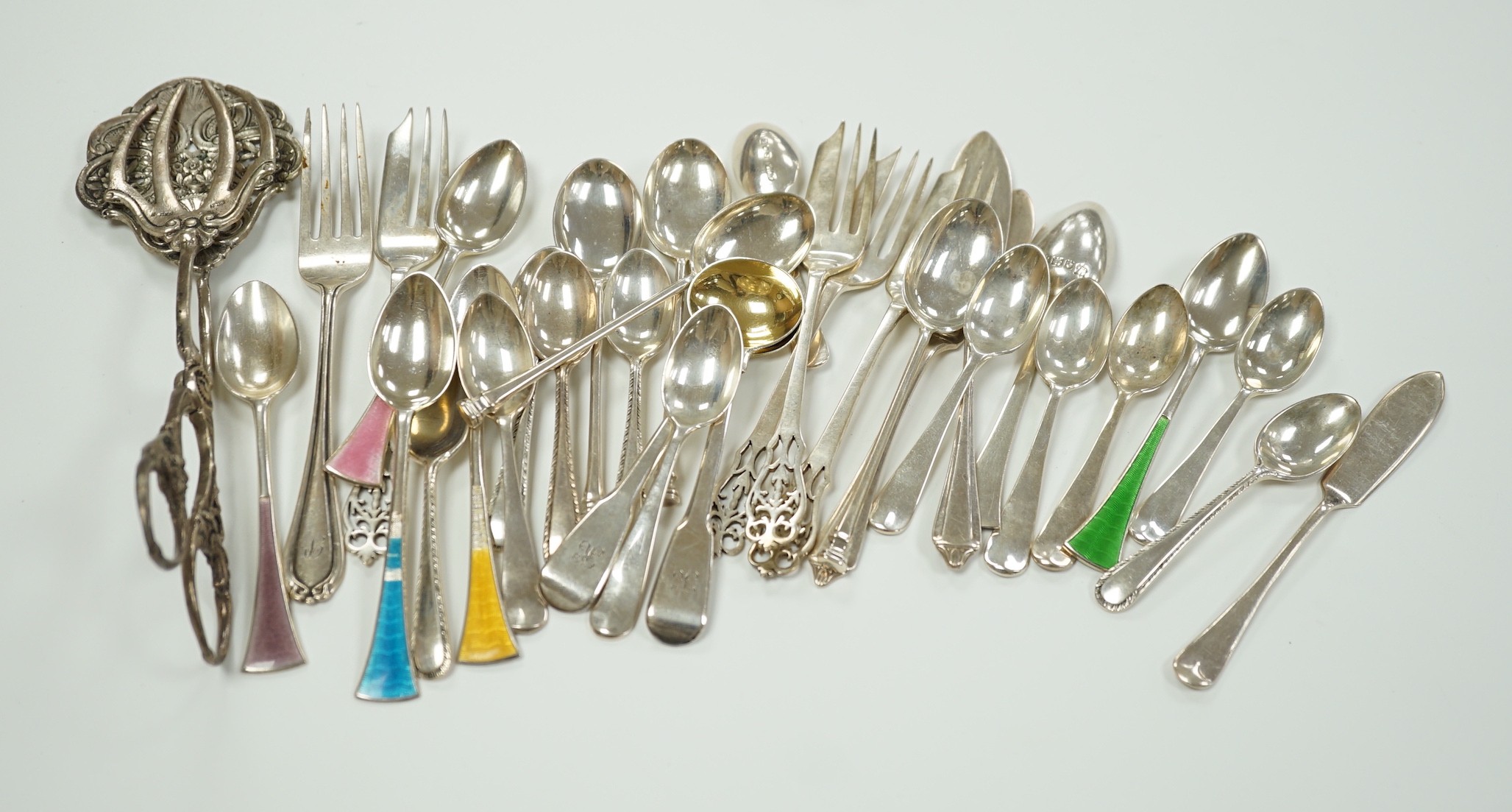 A small collection of assorted silver flatware including teaspoons, enamelled spoons(a.f.), butter knives, pastry forks and a pair of continental 830 white metal cake tongs, gross weight 14.4 oz.